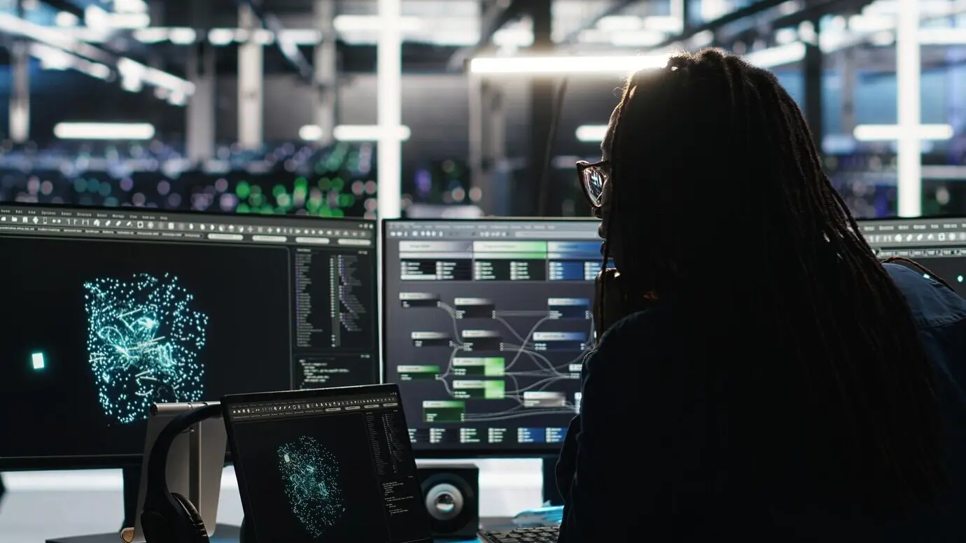 Técnico del centro de servidores que llega a la oficina y usa en el PC insights de visualización de IA.